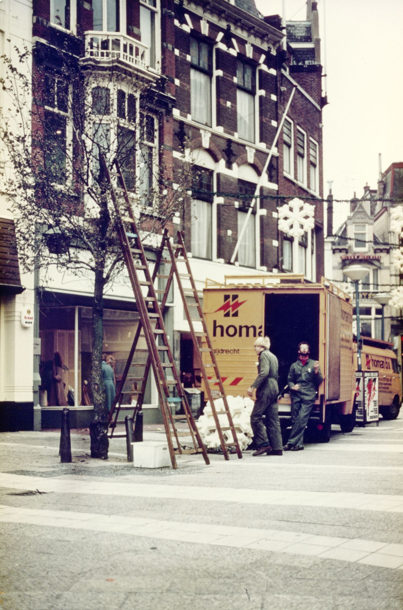 Homan-monteurs hangen feestverlichting op met ladder en bus
